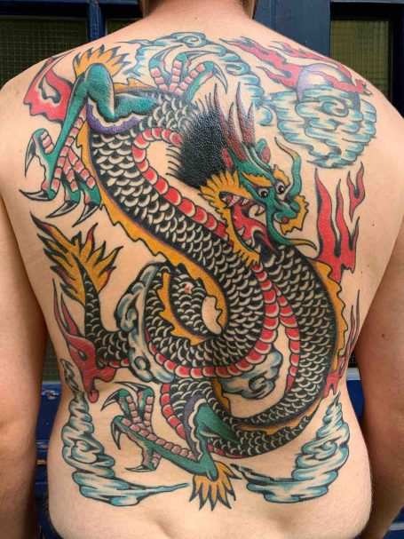Bunter Drachen-Tattoo auf dem Rücken mit starken Farben und dynamischem Design.