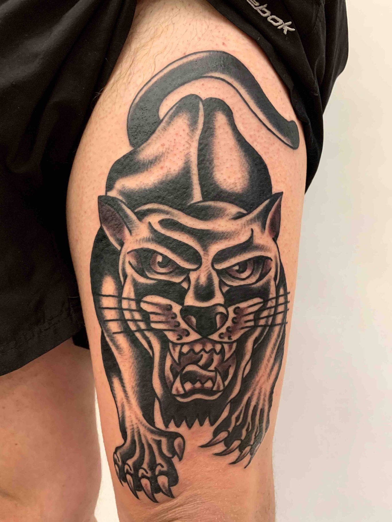 Traditional tattoo Berlin - tattoos by Mariano - Schwarze Panther-Tätowierung auf dem Oberschenkel mit aggressivem Ausdruck.