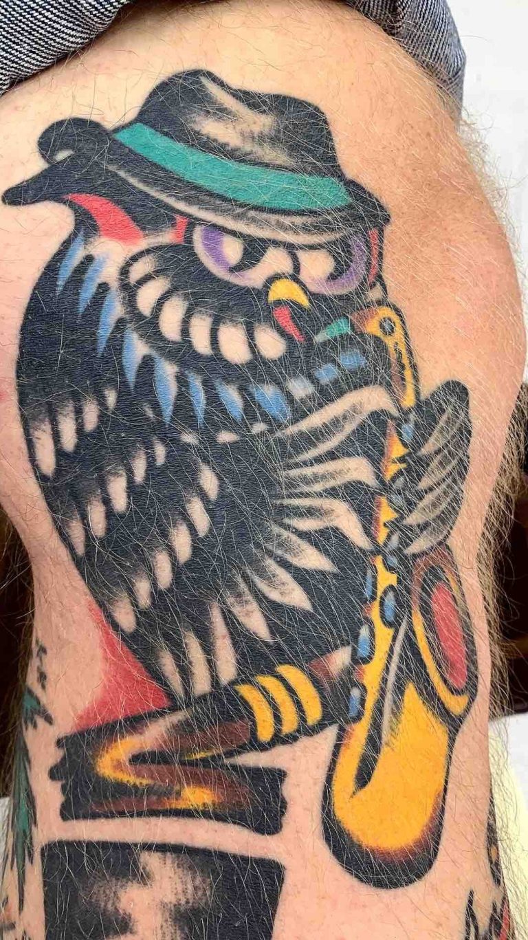 Traditional tattoo Berlin - Tattoos by Mariano - Bunte tätowierte Eule mit Hut, die Saxophon spielt.