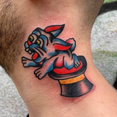 traditional tattoo artists in Berlin - Tattoos by Mariano - Tattoo eines cartoonhaften Hundes, der auf einem Zauberhut sitzt.
