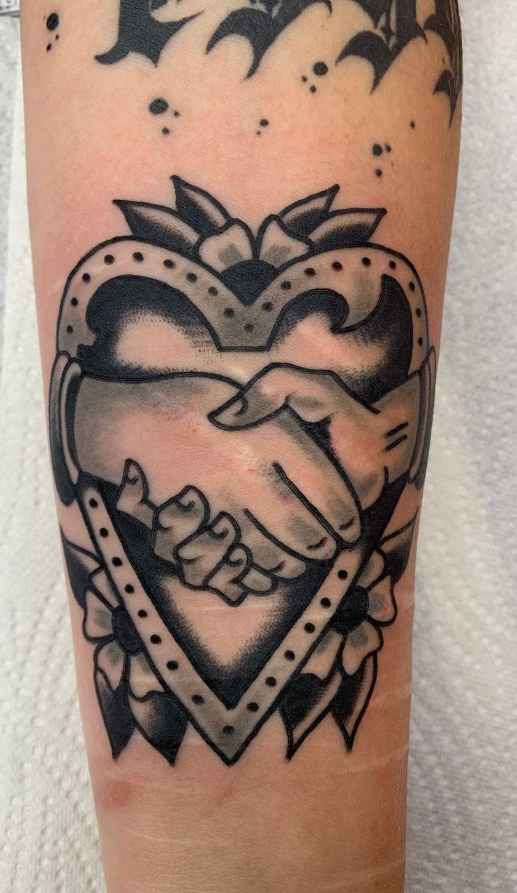 Traditional tattoo Berlin – Tattoos by Mariano – a heart with a handshake classic design in black and grey traditional tattoo