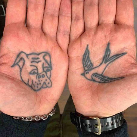 Tattoo eines Hundes auf der linken Hand, ein Vogel auf der rechten Hand.