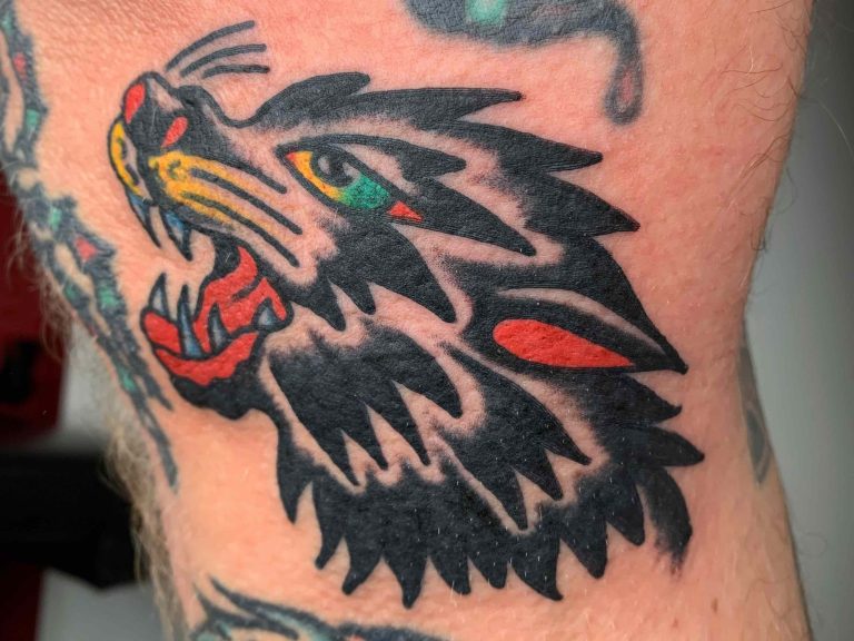 Traditional tattoo Berlin - Tattoos by Mariano - Tattoo of a wolf's head with a red mouth and green eyes.