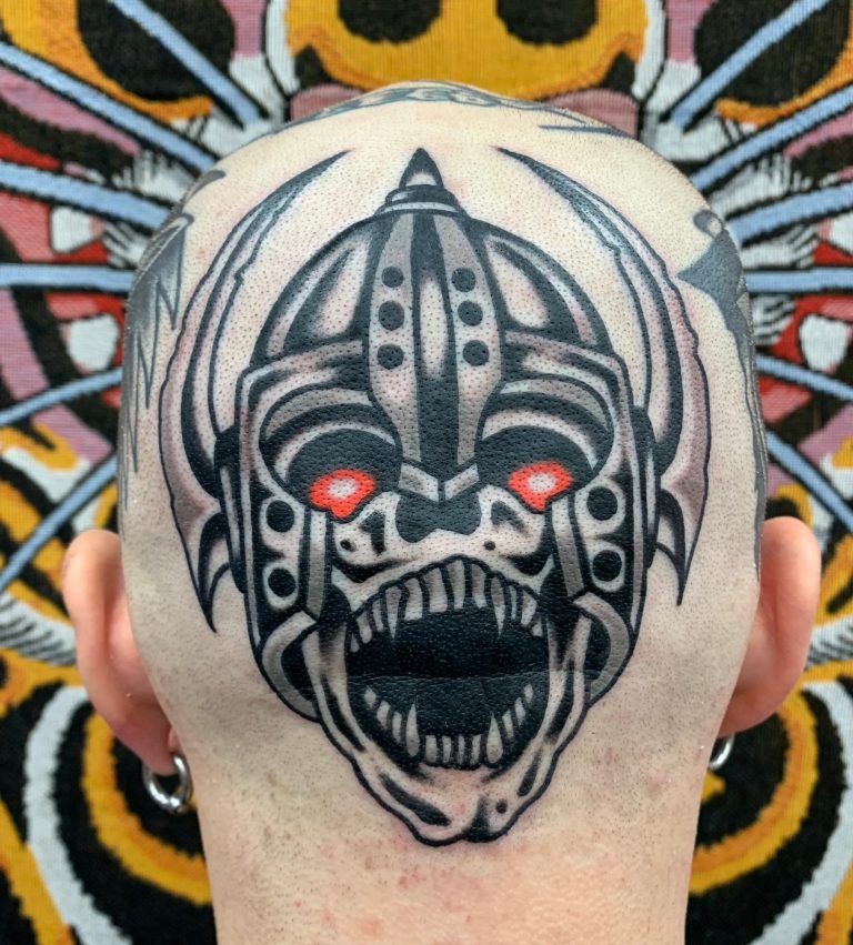Traditional tattoo Berlin – Tattoos by Mariano – Skull tattoo of a terrifying face with red eyes and sharp details.
