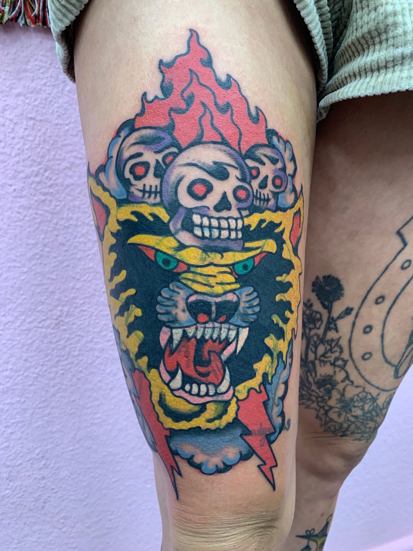 TIGER Traditional Tattoo Berlin - Tattoos by Mariano - Tattoo eines Löwenkopfes mit Totenschädeln und lodernden Flammen im Hintergrund.