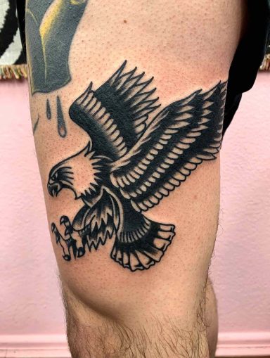 traditional tattoo artists in Berlin - Tattoos by Mariano - Schwarz-weißer Adler-Tattoo auf dem Oberschenkel, mit ausgebreiteten Flügeln.