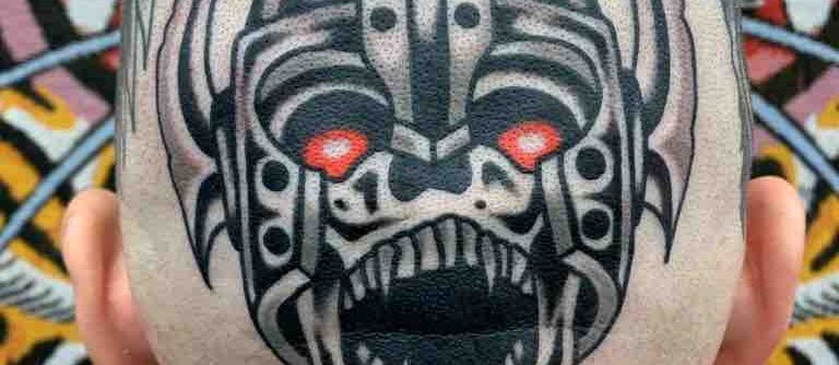 Traditional tattoo Berlin – Tattoos by Mariano – Skull tattoo of a terrifying, mask-like face with red eyes.